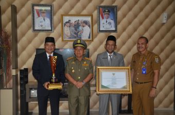 Kepala Bappeda Pelalawan menyerahkan Piagam dan piala Penghargaan Pembangunan Daerah Provinsi Riau Tahun 2018 Kepada Bupati Pelalawan